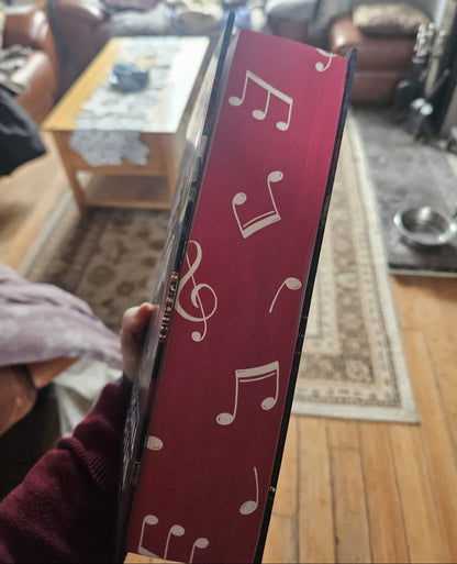 Red book with musical notes held in a living room