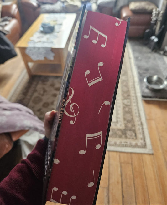 Red book with musical notes held in a living room